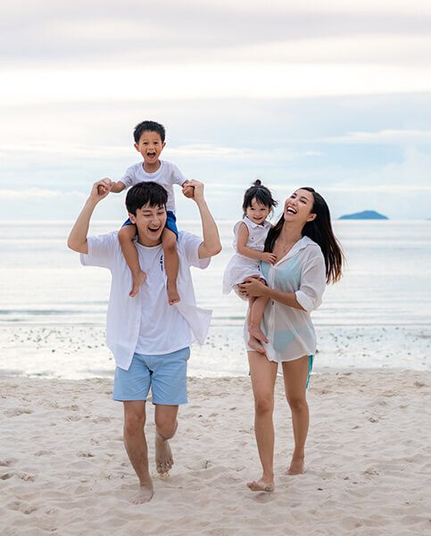Happy Asian family holidays during joyful father, mother, son and daughter walking together along summer sunset sea. Happy family travel on beach in holiday, Summer and vacation.